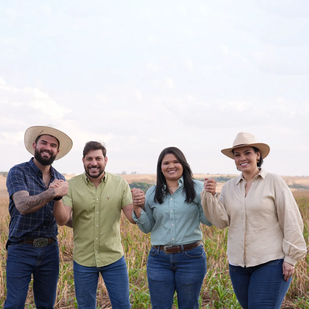 Os quatro sócios da BS Agro Capital de mãos dadas em uma lavoura